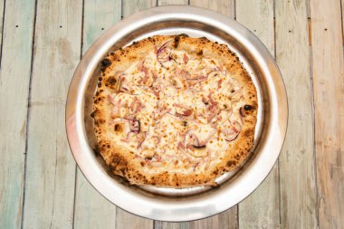 Pizza a la carbonara iyi pişmiş bir fırında pişirilmiş guanciale, mantar ve metal tepside kırmızı soğan ile birlikte.