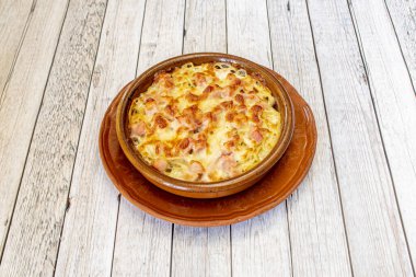 recipe for spaghetti carbonara with bacon and lots of melted cheese gratin in a clay bowl