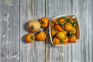 Tam olgunlaşmış mandalina sepeti, gevşek hurma ağaçları ve ahşap masada bir nar.