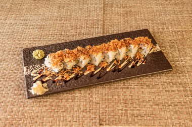 Uramaki dragon roll with crispy onion stuffed with surimi with wasabi and ginseng