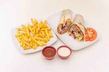 Durum menüsü ikiye bölünmüş ve alüminyum folyoyla sarılmış patates ve sosla süslenmiş ve bol miktarda kuzu kebabı, marul ve kırmızı lahana ile süslenmiş.