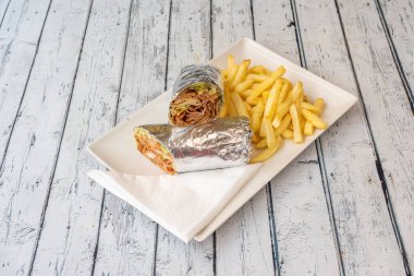 Alüminyum folyo ve kebap ile sarılmış patates kızartmasıyla süslenmiş marul ve sos.