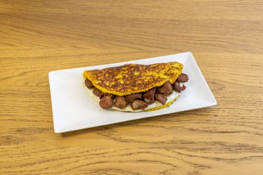 Erimiş peynirle doldurulmuş mısır cachapa ve beyaz tepside torreznos. Venezuela yemekleri