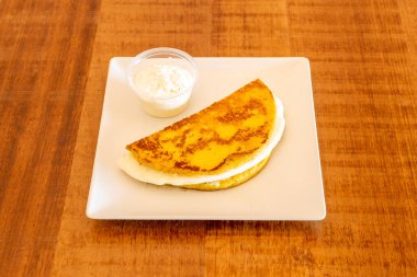 Erimiş queso freski ve şeffaf plastik bir kapta biraz daha queso freski ile dolu mısır cachapa. Venezuela yemekleri