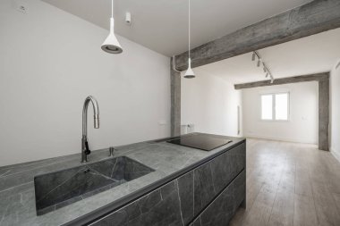 Mutfakta lavabo ve seramik hob ile mutfak adası. Kiralık bir dairede beton sütunlar ve kirişler açıkta.