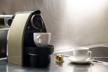 Kiralık bir evin mutfağındaki bir makinede kapsül kahvesi hazırlıyorum.