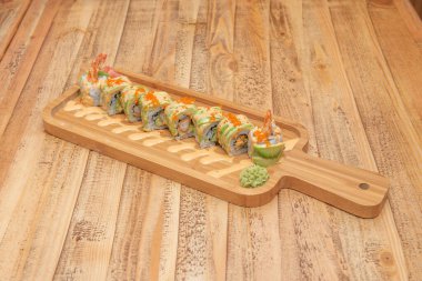 Uramaki ejder sarması karideslerle doldurulmuş tempura içinde dilimlenmiş avokado, sos, nori yosunu, balık yumurtası, wasabi ve ginseng.