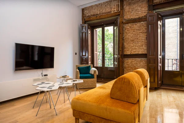 Living room with contemporary decor in a vintage building. Tv area with exposed brick wall in a vacation rental apartment