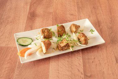 Beyaz soğanlı kuzu tikka masala şiş, kişniş ve maydanoz beyaz tepside