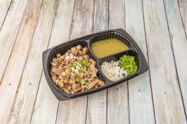 Beyaz soğanlı Carnitas menü tepsisi, kişniş ve nopales sosu ahşap masadaki eve servis konteynerinde.