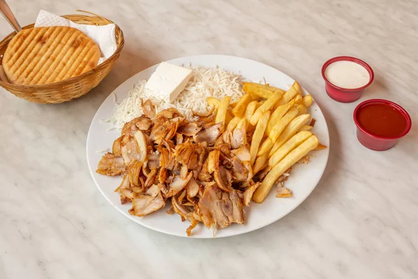 Menu kebab plate with chicken meat, fried potatoes, fresh cheese and basmati rice with pita bread and sauces