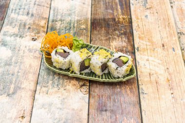 Kırmızı ton balığıyla doldurulmuş suşi uramaki dürümü ve yeşil yapraklı avokado.