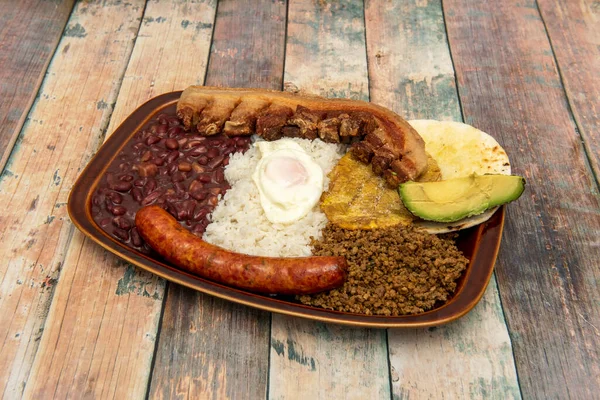 Popüler Kolombiya paisa tepsisi kızarmış sucuk ve chicharron, mısır gözlemesi, pastırma, olgun avokado, kızarmış yumurta ve beyaz pirinç ve şoför.