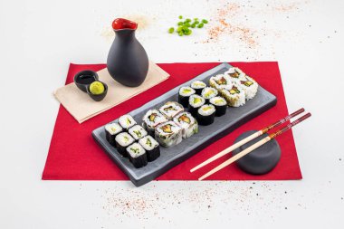 Assorted sushi platter, uramaki california roll, cream cheese and nori seaweed maki, sesame seeds and bowl with soy sauce, chopsticks, zucchini maki and ripe avocado, edamame beans