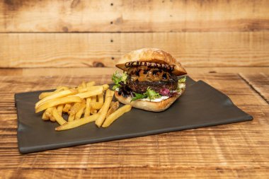 Karamelli soğanlı ördek köftesi, marul, mayonez, keçi peyniri ve yanında patates kızartması ile barbekü sosu.