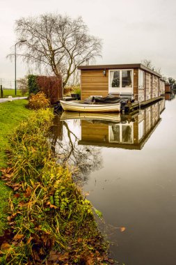 Amsterdam 'ın varoşlarındaki bir Hollanda kanalında yüzen ev ve yansıma