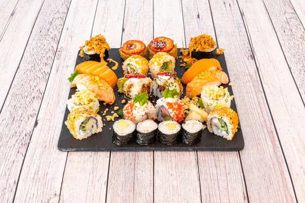 Assorted sushi tray with nori seaweed maki, uramaki california roll with masago roe, raw salmon nigiri,  salmon, crispy onion, cream cheese and horseradish, strawberry slices and ripe avocado