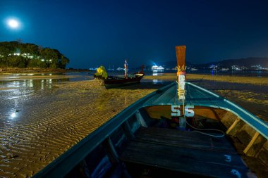 Uzun gece görüntüsü. Uzun kuyruklu tahta tekneler. Tayland sahilinin kumlarında.