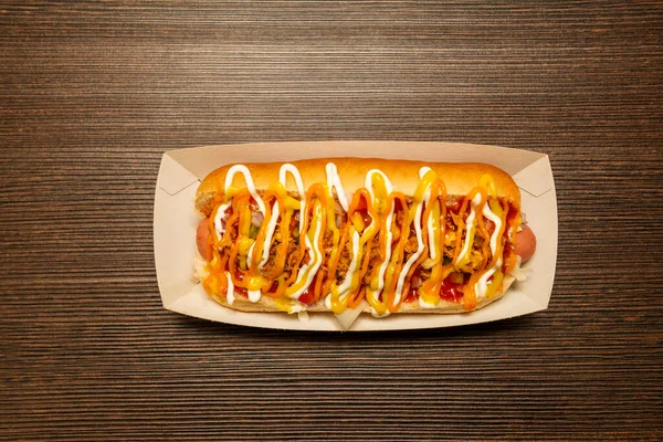 Imagen top view de hot dog con salchicha cubierta por un monton de salsas