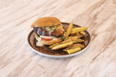 Sebze soslu sığır burger, erimiş peynir, yumurta ve patates kızartması mermer masada garnitür.