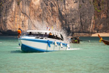 Tayland, Güneydoğu Asya 'daki Andaman Denizi' nin turkuaz sularında turistlerle dolu bir sürat teknesi.