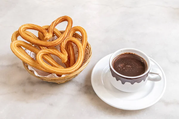 Popular Spanish breakfast or snack of chocolate with Madrid-style churros on white marble table