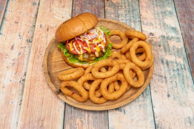 Kırmızı soğanlı sığır burger, erimiş peynir, hardal ve mayonez, domates dilimleri, buzdağı marulu ve bir sürü kızarmış soğan halkası.