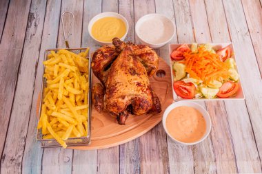 Kızarmış patates, sos ve doğranmış domatesle süslenmiş havuç salatalı tavuk menüsü.