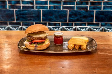 Eritilmiş Emmental peynirli sığır burger, marul, domates, soğan. Domates reçeli ve patates kızartması.