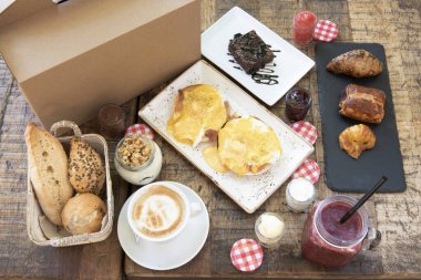 Benedict yumurtalı kahvaltı, çeşit çeşit ekmek, fındıklı yoğurt, reçelli ve çikolatalı krema, tereyağı ve çilekli tatlılar.