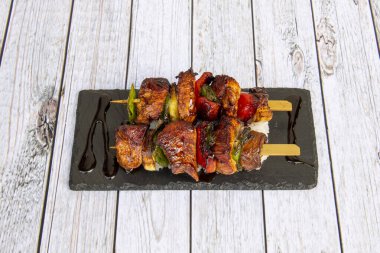 Sebzeli tavuk şişi, yakitori, beyaz pirinç yatağında yakisoba sosu ve siyah levha.