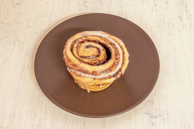 Kahverengi tabakta kremalı Norveç tarçınlı rulo.