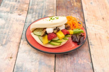 Krem peynirli bao sandviç, füme yılan balığı, avokado, salatalık dilimleri ve marullu mango.