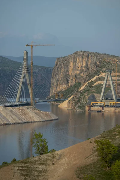 General view of the construction process of a suspension bridge to cross a lake between mountains