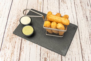 Yeni pişmiş Venezuela 'lı küçük metal bir sepet. Karakteristik altın renklerini ve kırsal ahşap bir zeminde kırıldığında uzanan erimiş peynirlerini sergiliyor.