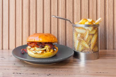 Çift köfteli klasik hamburger, turşu ve kızarmış soğan halkalarıyla birlikte yumuşak sarı brioche ekmeği.