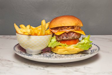 Parlak brioche ekmeği, erimiş çedar peyniri, taze marul ve domatesli sulu sığır burger.