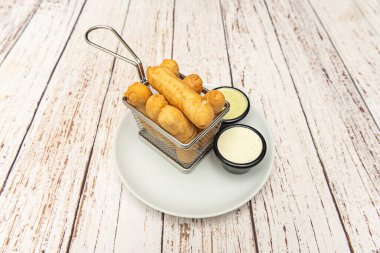 Küçük metal sepet taze kızarmış Venezuela parmaklarıyla dıştan çıtır çıtır dokularını ve içeriden erimiş peynirlerini gösteriyor.