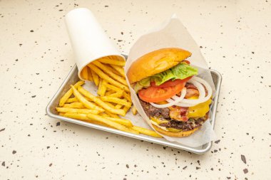 Simgesel biftekli zanaatkar burger, eritilmiş Cantal peyniri, armut domatesli ve kızarmış brioche ekmeğinde romaine marulu.