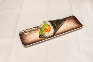 Somon ve krem peynirli uramaki soğanlı, karışık susam tohumlu, porselen üzerine sarılmış.