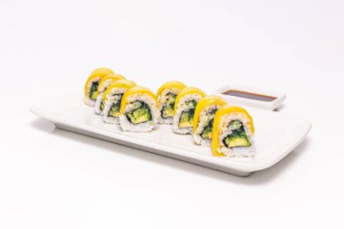 Taze kişniş soslu mango uramaki, porselen üzerinde kavrulmuş susam tohumları.