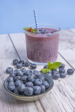 Yaban mersinli kompozisyon ve böğürtlen ve klorellalı smoothie eski bir bambu tahtasında