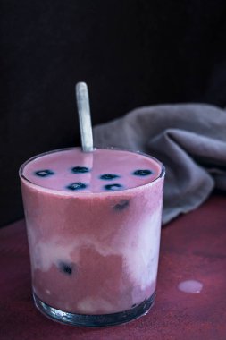 Böğürtlenli, kendine özgü çiçekleri ve vernikli çam ağacından bir masada yabanmersini ve hindistan cevizli smoothie.