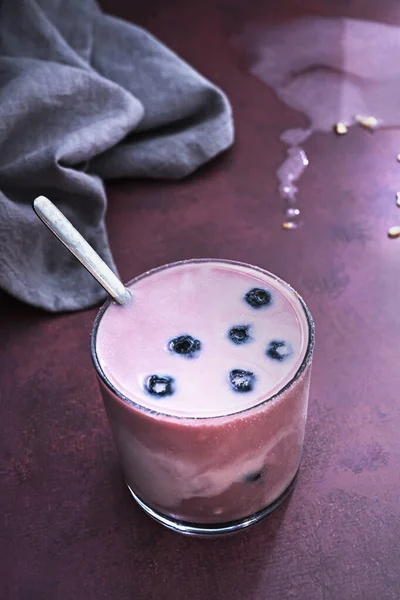 Böğürtlenli, yaban mersinli ve kavrulmuş badem smoothie ile balmumu ahşap bir sörfte kompozisyon