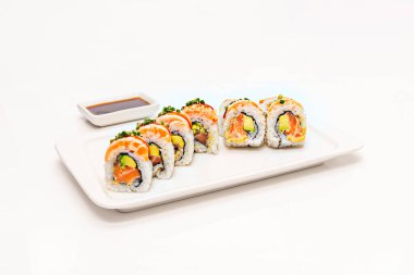 Avokado ve soya soslu kuşkonmaz uramaki, kare porselen bir tabakta.