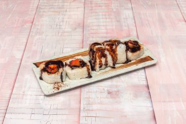 biberli uramaki teriyaki, siyah susam tohumları sarılmış, porselen üzerinde