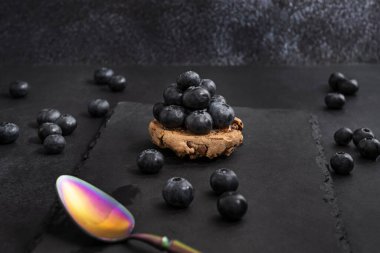 Gece yarısı mavi kadife arka planda yabanmersini ve kontrollü oksitlenme gümüş kaşığı.