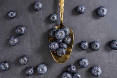 Koyu lacivert kadife arka planda oksitlenmiş gümüş kaşıklı olgun yaban mersini yığını.