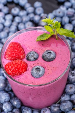 Mor renkli yaban mersini ve yaban mersini ve acerola kokteyli kırsal çam ağacından yapılmış bir masada.