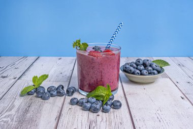 Doğal ışıkta parlayan yaban mersini ve kırsal bir çam ağacından yapılmış masada yaban mersini ve kibrit suyu.